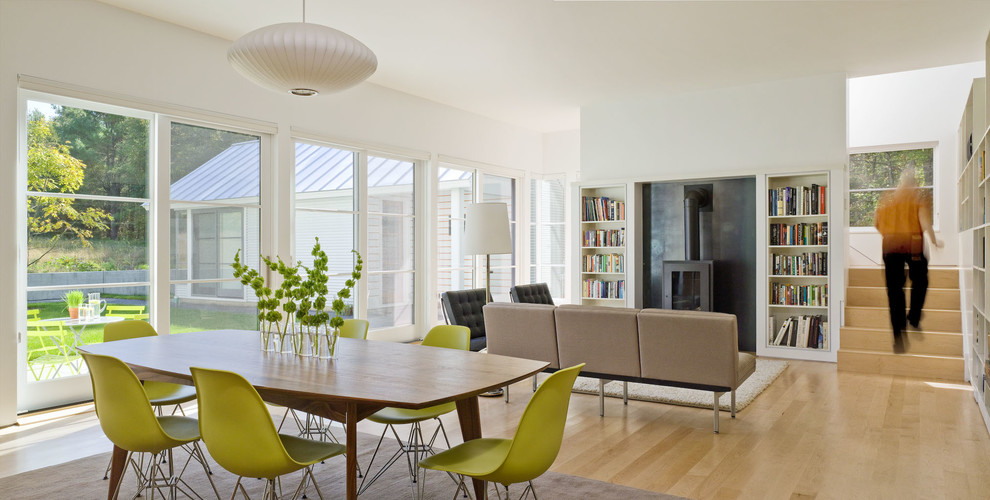 Foto di un soggiorno design aperto con libreria, pareti bianche, parquet chiaro, nessuna TV e stufa a legna