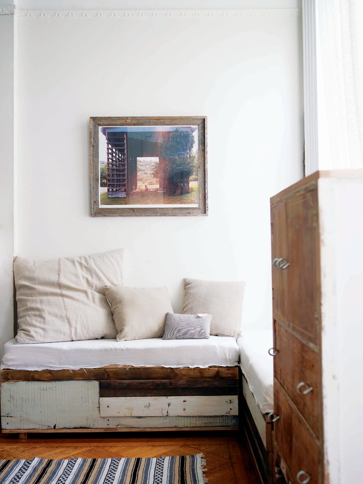 Cette image montre un salon style shabby chic avec un mur blanc et un sol en bois brun.