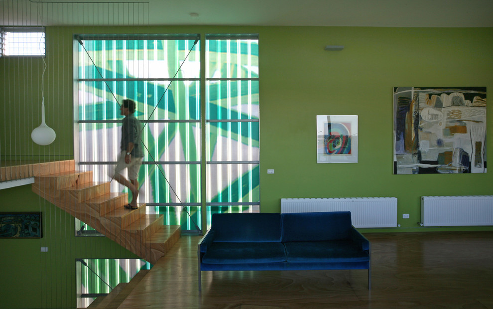 Mittelgroßes, Fernseherloses Modernes Wohnzimmer ohne Kamin, im Loft-Stil mit grüner Wandfarbe und Sperrholzboden in Melbourne