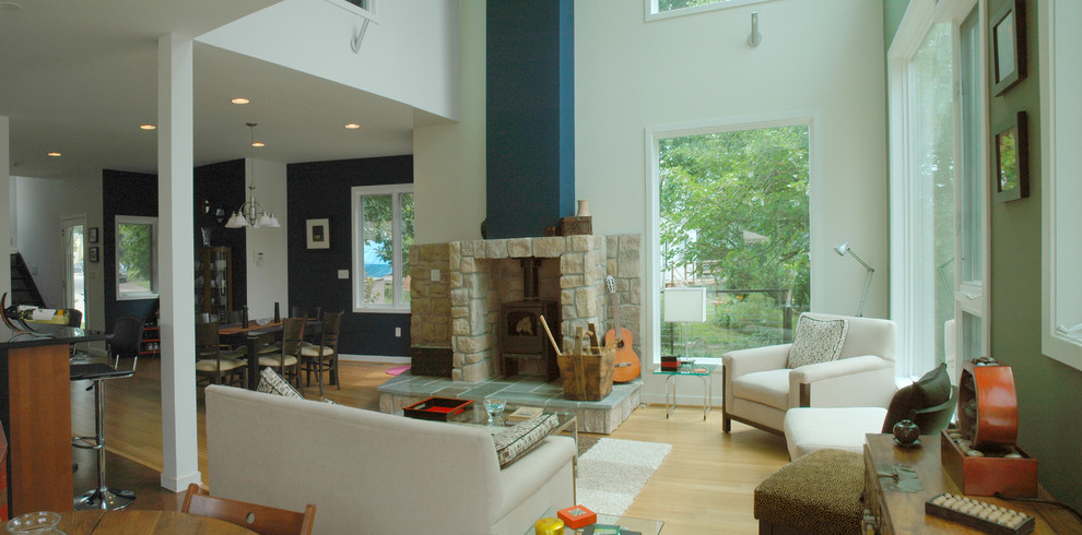 Foto di un soggiorno minimalista di medie dimensioni e stile loft con pareti verdi, parquet chiaro, camino classico e cornice del camino in pietra