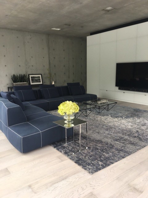 Idée de décoration pour un très grand salon minimaliste ouvert avec une salle de réception, un mur gris, un téléviseur encastré, parquet clair et un sol marron.