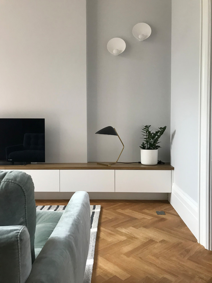 Example of a huge minimalist enclosed medium tone wood floor and brown floor living room design in London with blue walls and a media wall