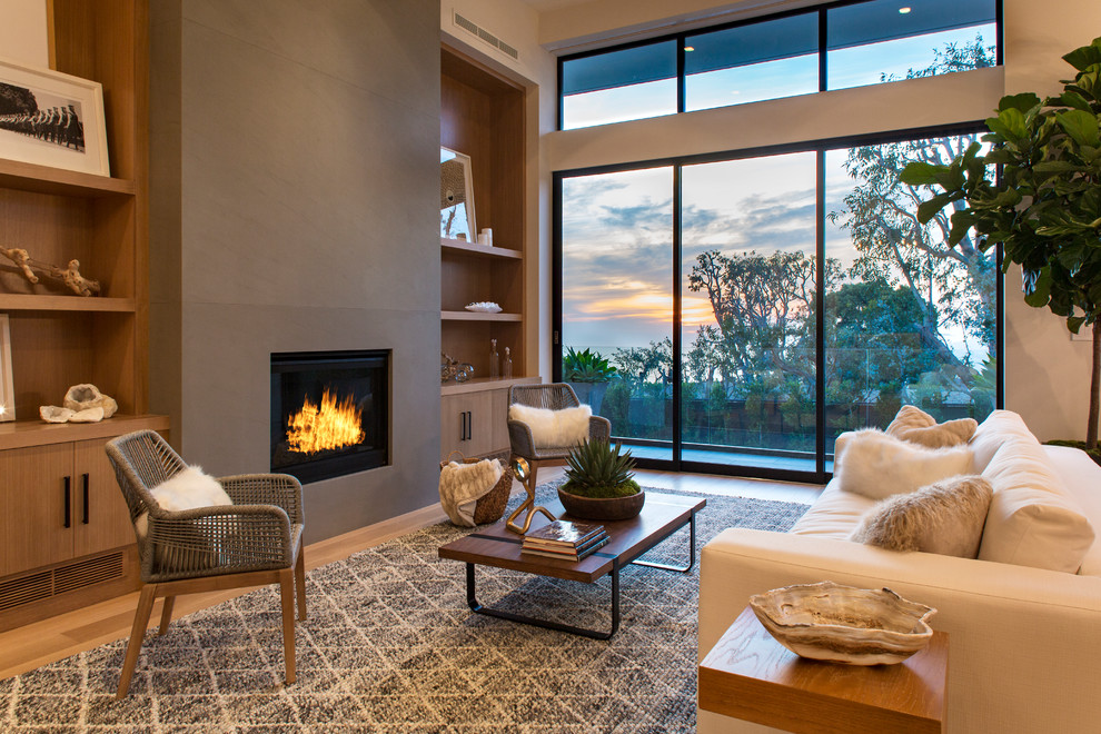 Cette photo montre un salon tendance avec un mur beige, un sol en bois brun et une cheminée standard.