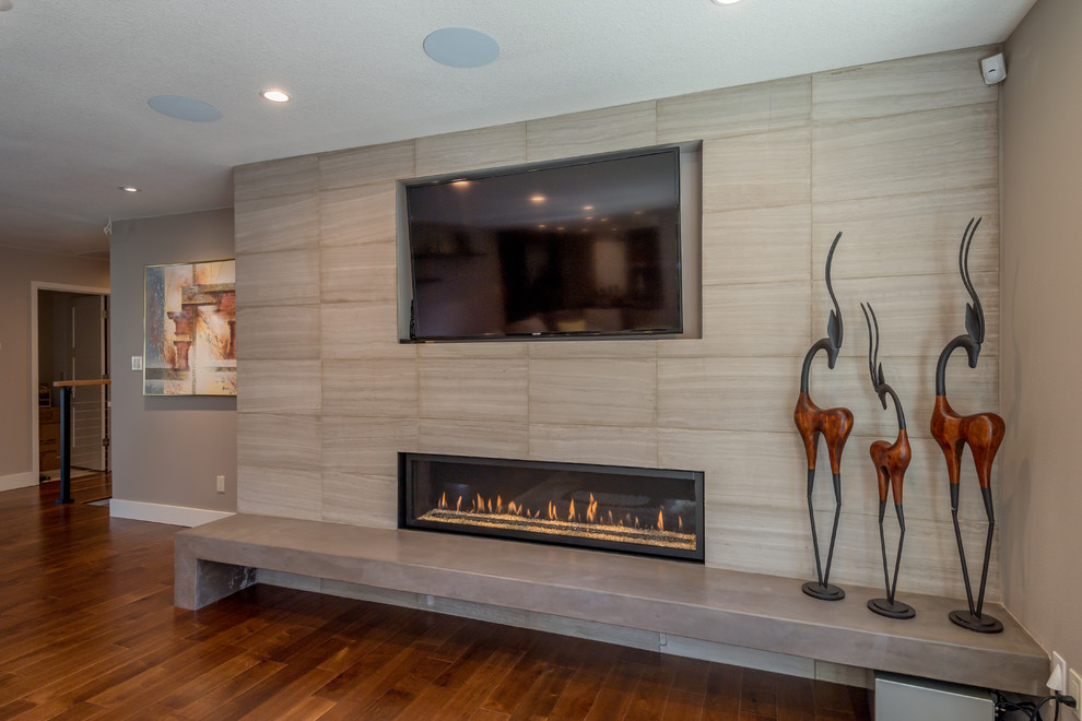 Exempel på ett stort modernt allrum med öppen planlösning, med grå väggar, mellanmörkt trägolv, en bred öppen spis, en spiselkrans i trä, en väggmonterad TV och brunt golv