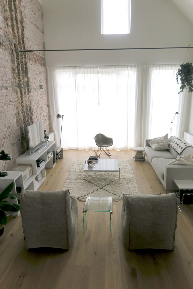 Пример оригинального дизайна: открытая гостиная комната среднего размера в стиле лофт с домашним баром, разноцветными стенами, светлым паркетным полом, отдельно стоящим телевизором и коричневым полом без камина