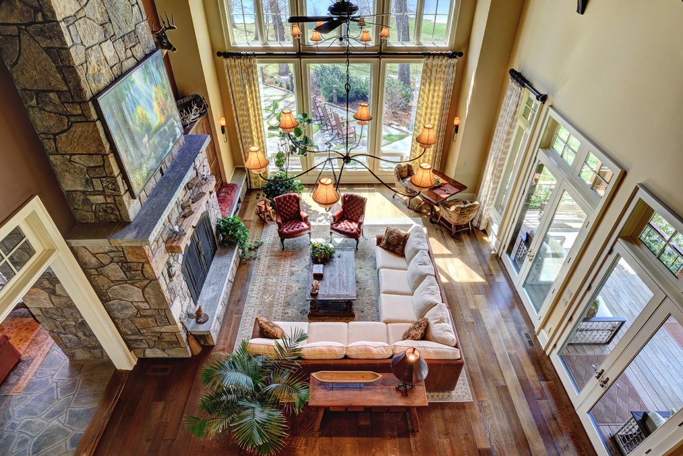 This is an example of a rustic living room in Other with beige walls, medium hardwood flooring, a standard fireplace, a stone fireplace surround and a concealed tv.