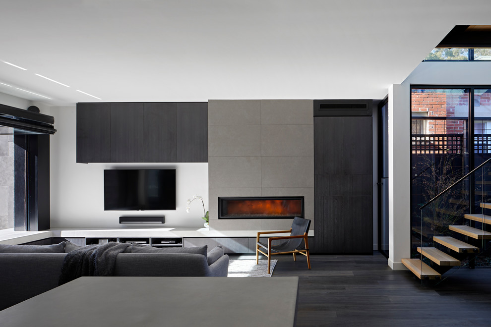 Exemple d'un salon tendance avec un mur blanc, parquet foncé, une cheminée ribbon, un téléviseur fixé au mur et un sol gris.