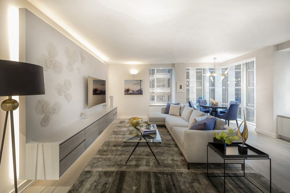 Стильный дизайн: парадная, открытая гостиная комната в современном стиле с бежевыми стенами, светлым паркетным полом, телевизором на стене и ковром на полу - последний тренд