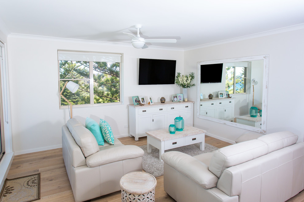 На фото: маленькая гостиная комната в морском стиле с белыми стенами, светлым паркетным полом и телевизором на стене для на участке и в саду с