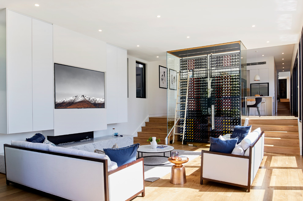Ejemplo de salón abierto contemporáneo con paredes blancas, suelo de madera en tonos medios, televisor colgado en la pared y suelo marrón