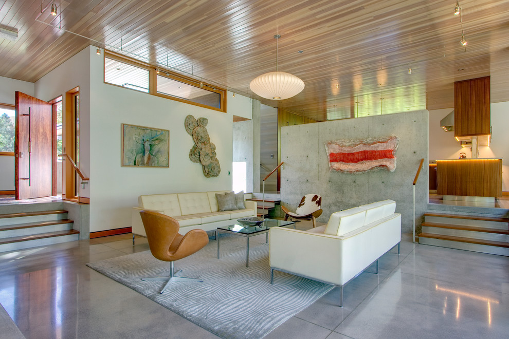 This is an example of a contemporary open plan living room in Seattle with white walls and concrete flooring.