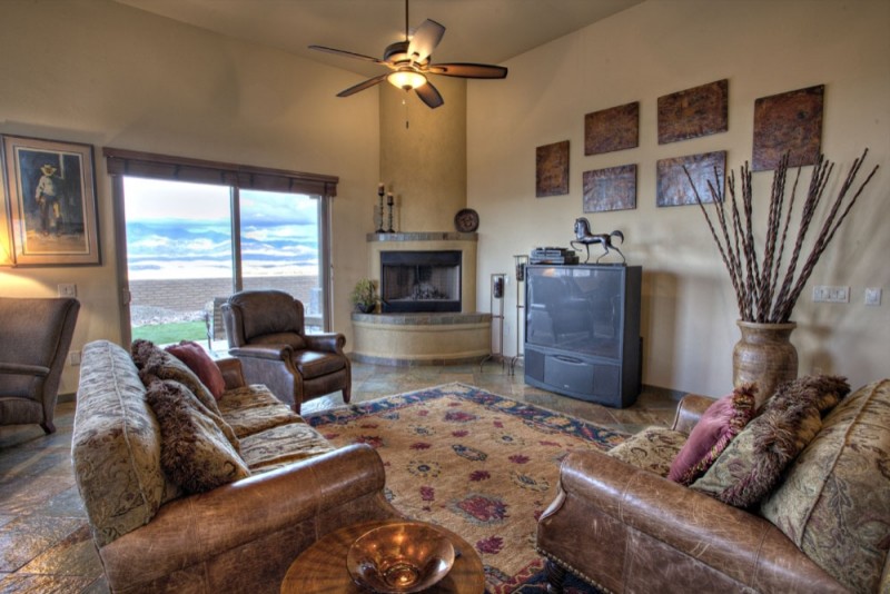 Cette photo montre un grand salon sud-ouest américain ouvert avec un mur beige, une cheminée d'angle, un manteau de cheminée en plâtre et un téléviseur indépendant.