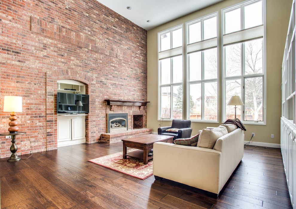 This is an example of a large traditional open plan living room in Denver with medium hardwood flooring, a standard fireplace and a wall mounted tv.
