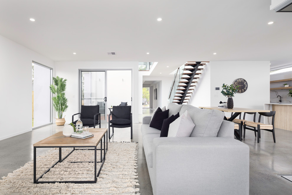 Offenes Skandinavisches Wohnzimmer mit weißer Wandfarbe, Betonboden und grauem Boden in Brisbane