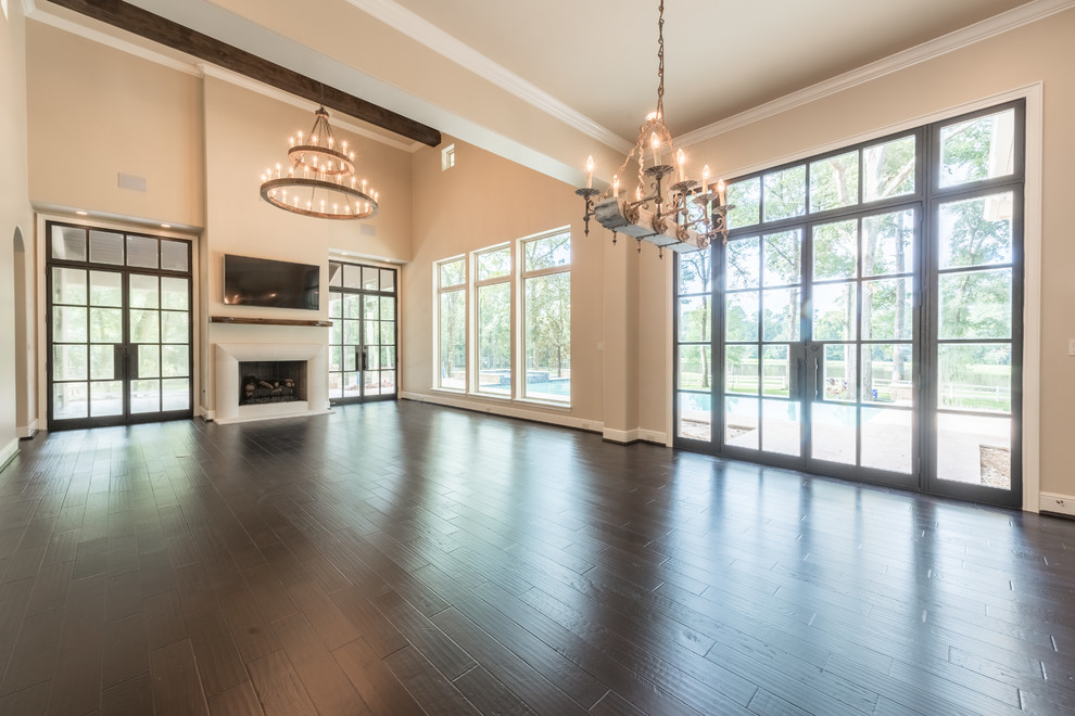 Großes, Offenes Klassisches Wohnzimmer mit beiger Wandfarbe, dunklem Holzboden, Kamin, verputzter Kaminumrandung, TV-Wand und braunem Boden in Houston