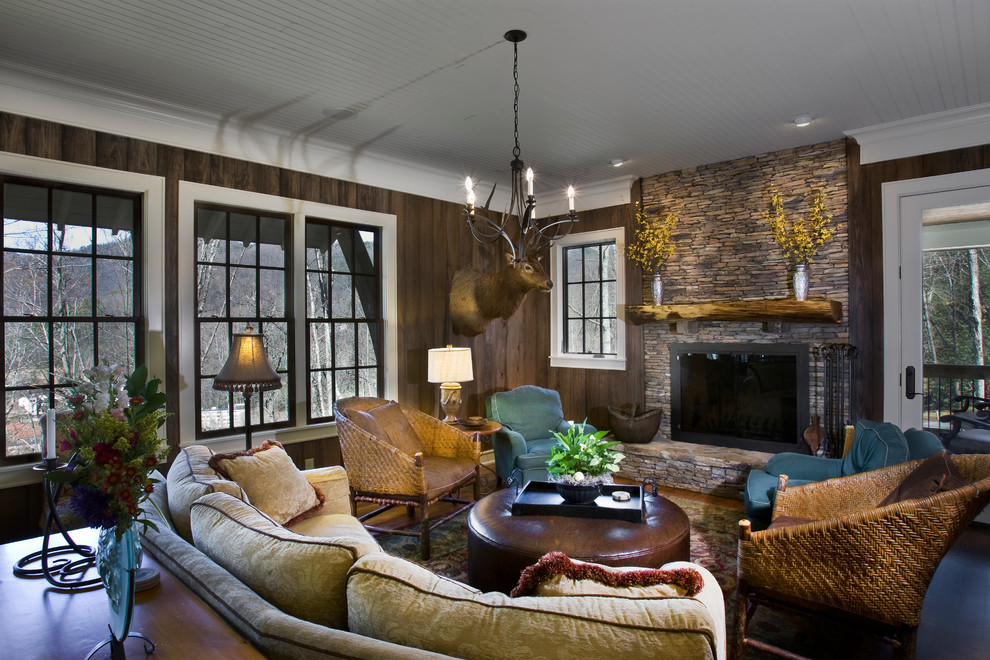 На фото: открытая гостиная комната среднего размера в стиле рустика с коричневыми стенами, темным паркетным полом, стандартным камином и фасадом камина из камня с