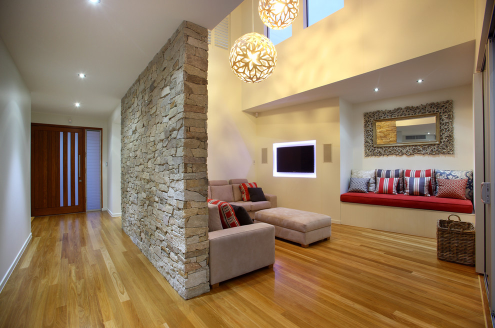Пример оригинального дизайна: гостиная комната в современном стиле с бежевыми стенами, телевизором на стене и паркетным полом среднего тона