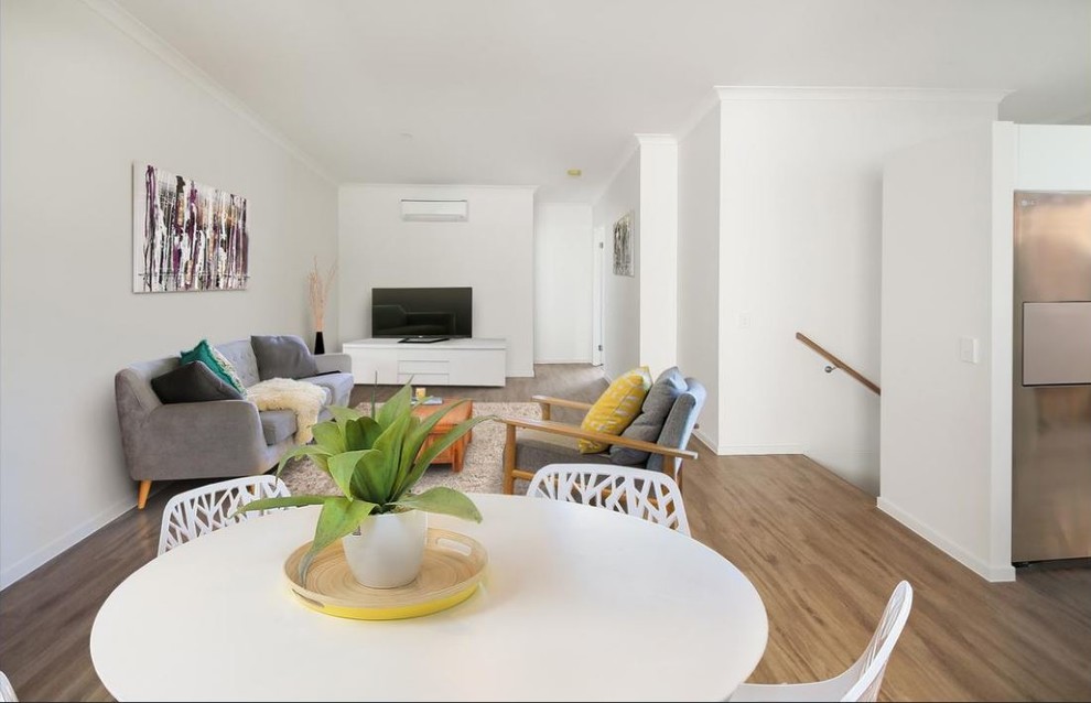 Idee per un piccolo soggiorno design aperto con sala formale, pareti gialle, parquet chiaro, TV autoportante e pavimento marrone