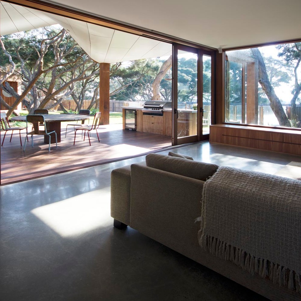 Idéer för ett modernt vardagsrum, med betonggolv, en standard öppen spis, en spiselkrans i trä och en fristående TV