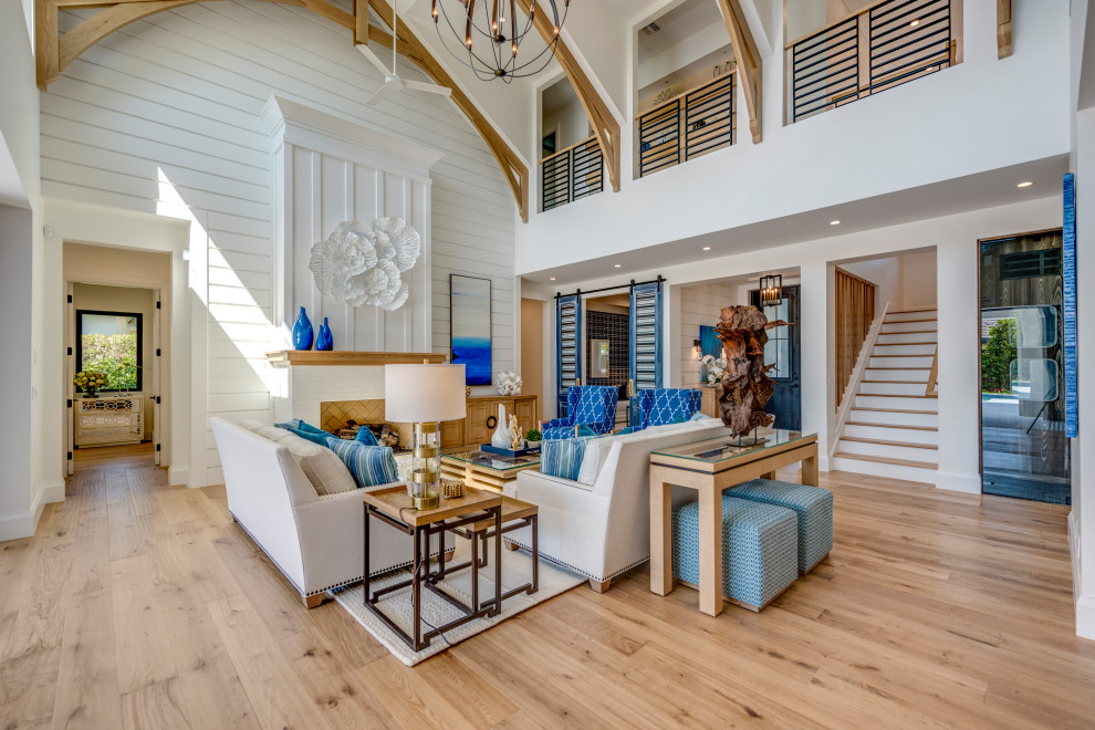 Großes, Offenes Maritimes Wohnzimmer mit weißer Wandfarbe, braunem Holzboden, Kamin, Kaminumrandung aus Backstein und braunem Boden in Miami