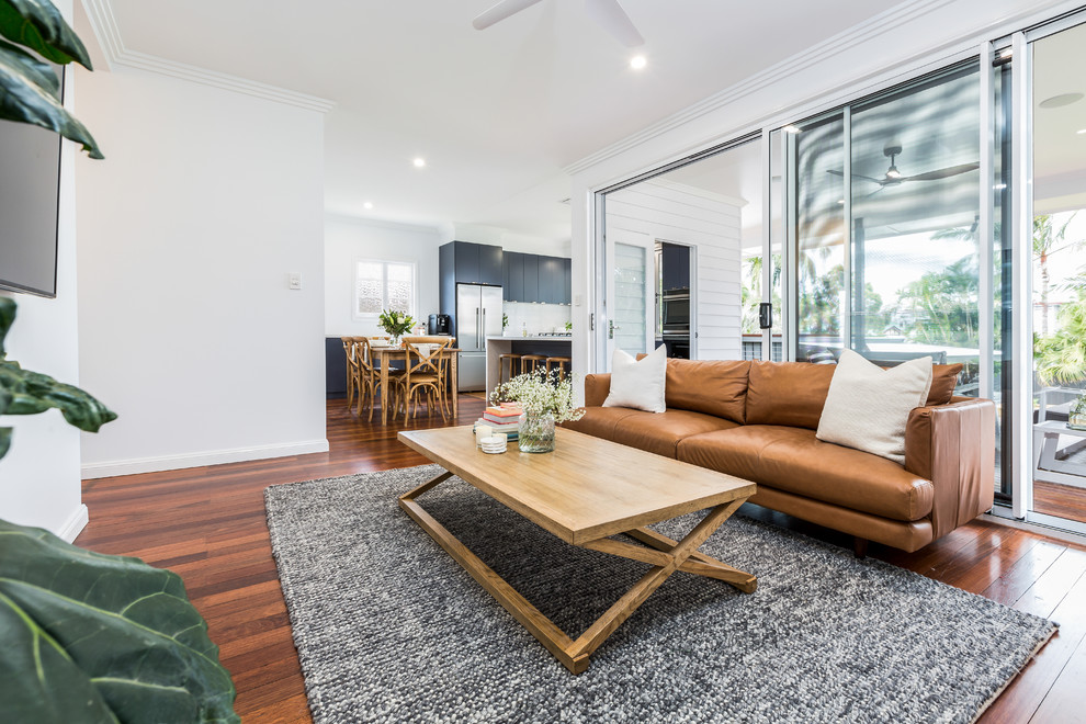 Kleines, Offenes Klassisches Wohnzimmer mit weißer Wandfarbe, braunem Holzboden, TV-Wand und braunem Boden in Brisbane