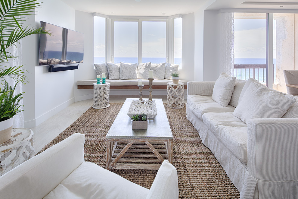 Стильный дизайн: гостиная комната в морском стиле с белыми стенами, телевизором на стене и бежевым полом без камина - последний тренд