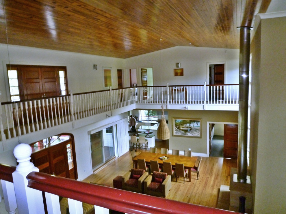 Пример оригинального дизайна: большая открытая гостиная комната в морском стиле с домашним баром, белыми стенами, светлым паркетным полом, подвесным камином, фасадом камина из камня и деревянным потолком
