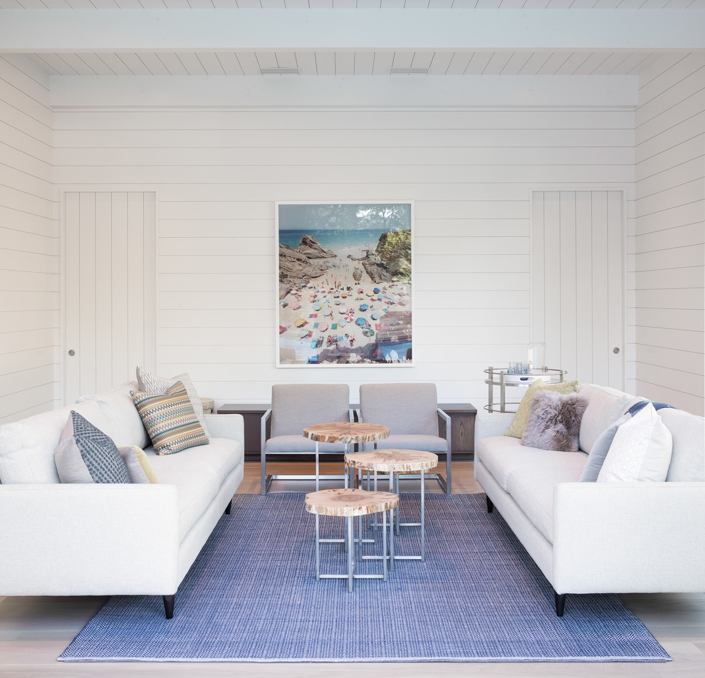 Foto på ett maritimt vardagsrum, med vita väggar, ljust trägolv och beiget golv