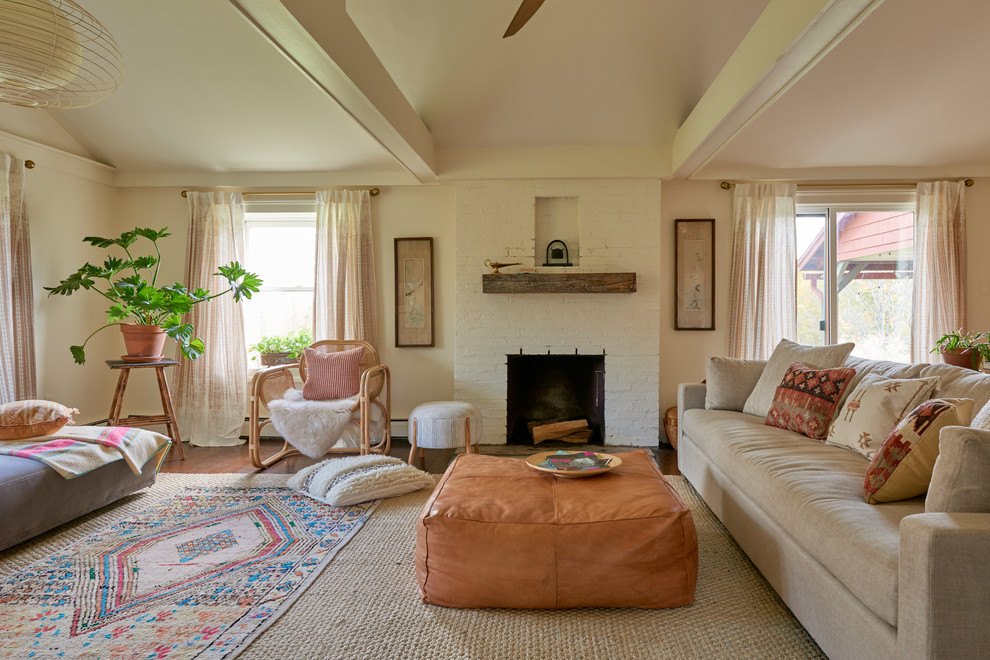 Foto de salón campestre sin televisor con paredes beige, suelo de madera en tonos medios, todas las chimeneas, marco de chimenea de ladrillo y vigas vistas