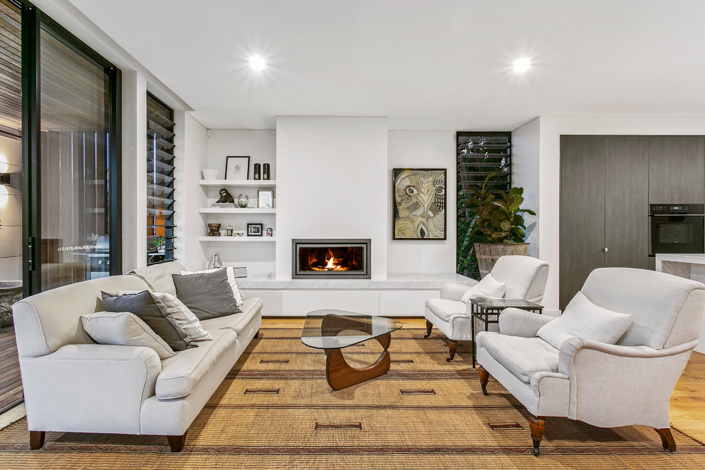 Mittelgroßes, Offenes, Repräsentatives Modernes Wohnzimmer mit weißer Wandfarbe, hellem Holzboden, Gaskamin, verputzter Kaminumrandung und beigem Boden in Sydney