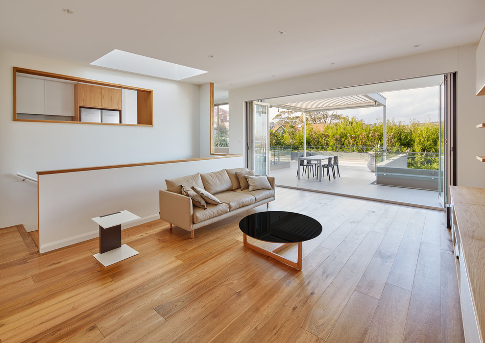 Cette image montre un salon minimaliste avec un mur blanc et un sol en bois brun.