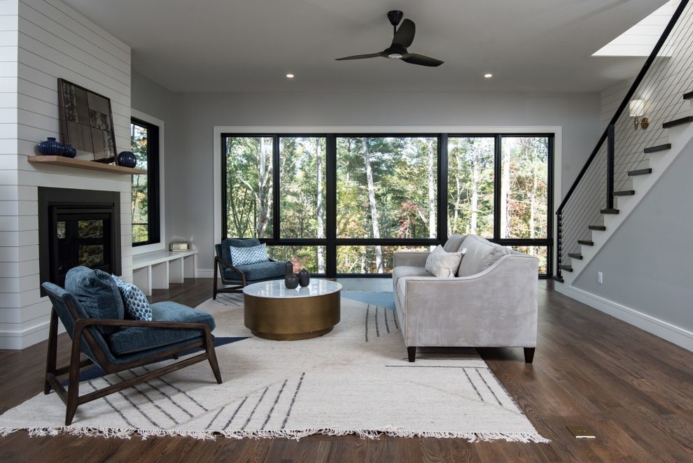 Источник вдохновения для домашнего уюта: открытая гостиная комната среднего размера в стиле кантри с серыми стенами, паркетным полом среднего тона, двусторонним камином, фасадом камина из дерева и коричневым полом
