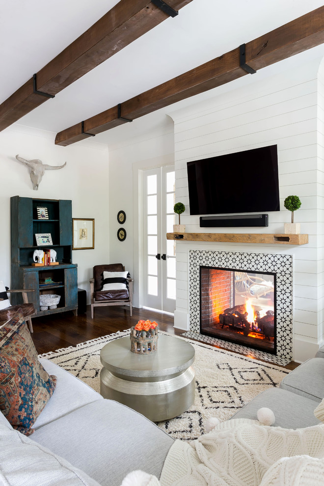 Exemple d'un salon moderne de taille moyenne et ouvert avec un mur blanc, un sol en bois brun, une cheminée double-face, un manteau de cheminée en carrelage, un téléviseur fixé au mur et un sol marron.