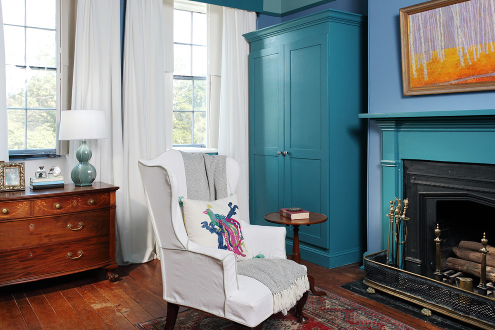 Cette image montre un salon bohème de taille moyenne et fermé avec une salle de réception, un mur bleu, un sol en bois brun, une cheminée standard et un manteau de cheminée en métal.