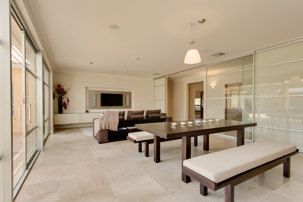 Ispirazione per un grande soggiorno minimalista aperto con pareti beige, pavimento in travertino e parete attrezzata