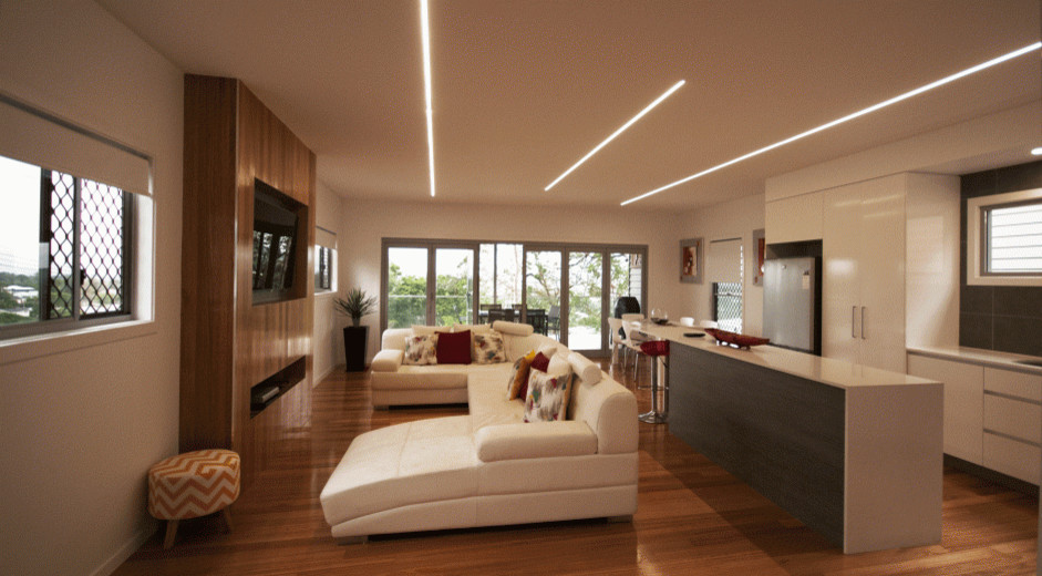 Modelo de salón contemporáneo con paredes blancas, suelo de madera en tonos medios, chimenea lineal, marco de chimenea de madera y pared multimedia