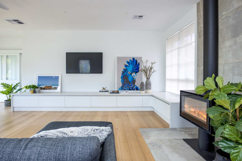 Ejemplo de salón abierto escandinavo de tamaño medio con paredes blancas, suelo de madera en tonos medios, todas las chimeneas y televisor colgado en la pared