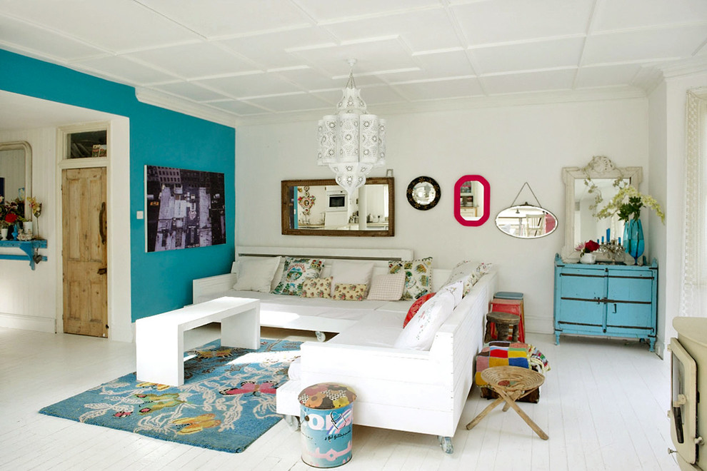 Idée de décoration pour un salon bohème avec un mur bleu et parquet peint.