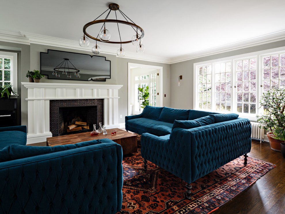 Пример оригинального дизайна: изолированная гостиная комната в классическом стиле с серыми стенами, темным паркетным полом, стандартным камином и синим диваном