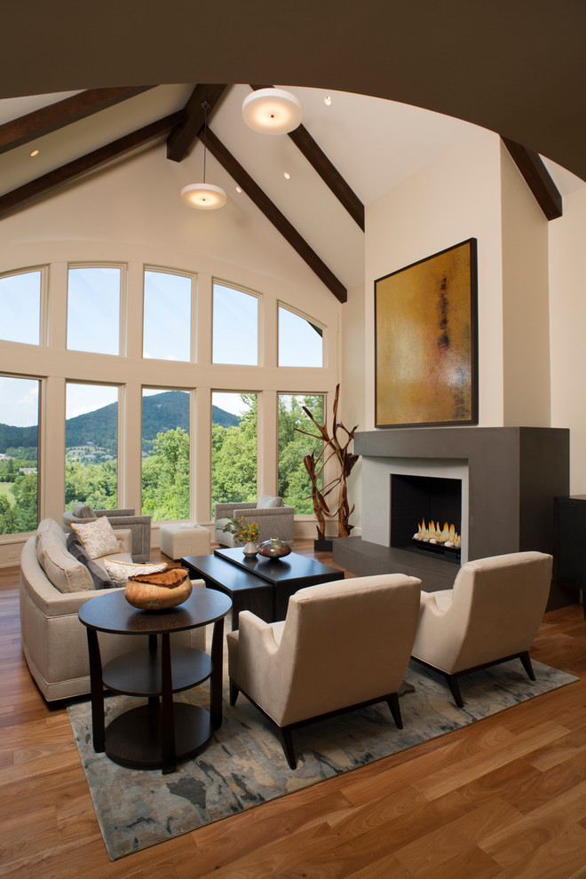 Cette photo montre un grand salon tendance ouvert avec un mur beige, un sol en bois brun, une cheminée standard, un manteau de cheminée en béton et aucun téléviseur.