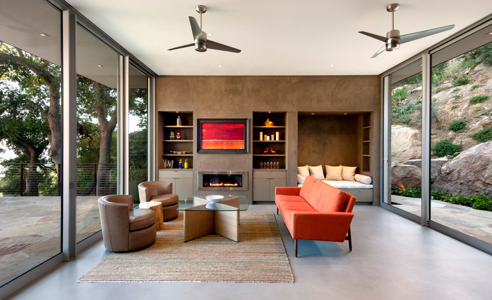 サンタバーバラにあるコンテンポラリースタイルのおしゃれなリビング (横長型暖炉、茶色い壁、赤いソファ) の写真
