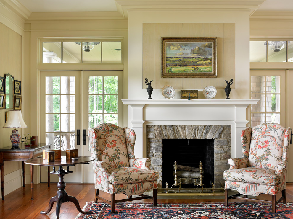 Foto de salón clásico con paredes beige, suelo de madera en tonos medios, todas las chimeneas, marco de chimenea de piedra y alfombra