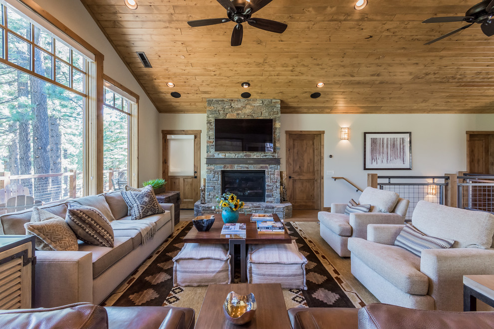 Inspiration for a rustic open plan living room in Other with white walls, medium hardwood flooring, a standard fireplace, a stone fireplace surround, a wall mounted tv and brown floors.