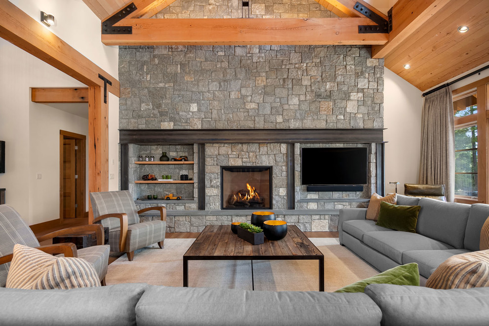 Photo of a medium sized rustic formal open plan living room in Seattle with beige walls, medium hardwood flooring, a standard fireplace, a stone fireplace surround, a wall mounted tv and brown floors.