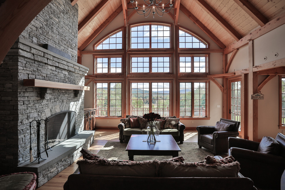 Cette image montre un salon traditionnel ouvert avec un mur beige, un sol en bois brun, une cheminée standard et un manteau de cheminée en pierre.