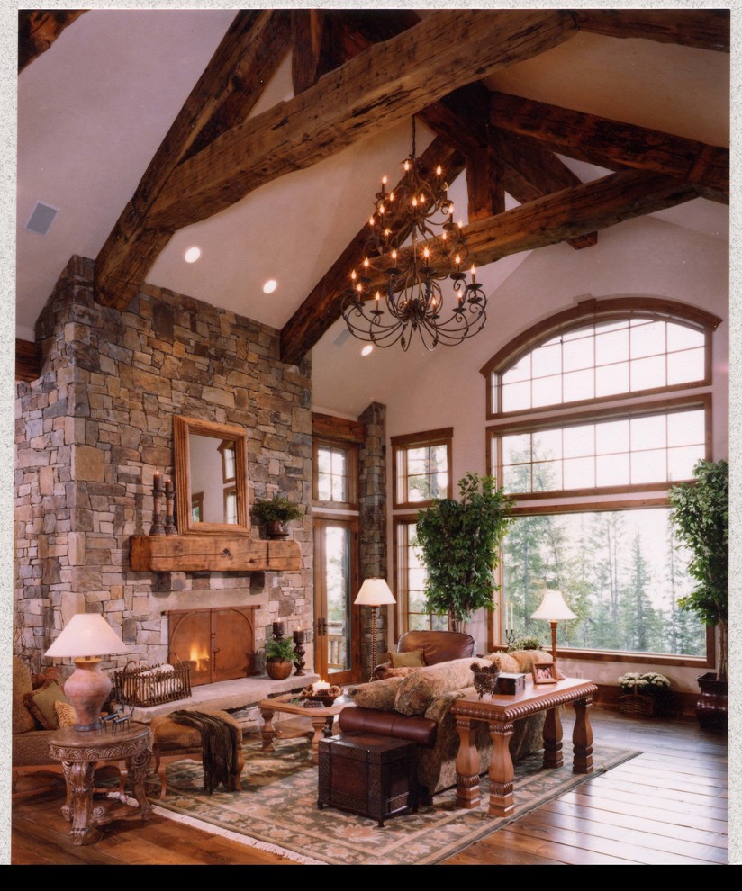 Cette photo montre un très grand salon montagne ouvert avec un mur multicolore, un sol en bois brun, une cheminée standard et un manteau de cheminée en pierre.