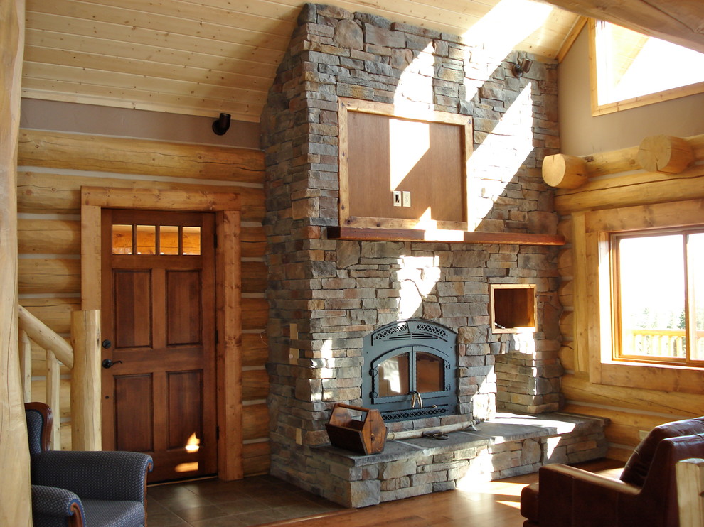 Modelo de salón tipo loft de estilo americano de tamaño medio con paredes marrones, suelo de madera oscura, estufa de leña, marco de chimenea de piedra y televisor colgado en la pared
