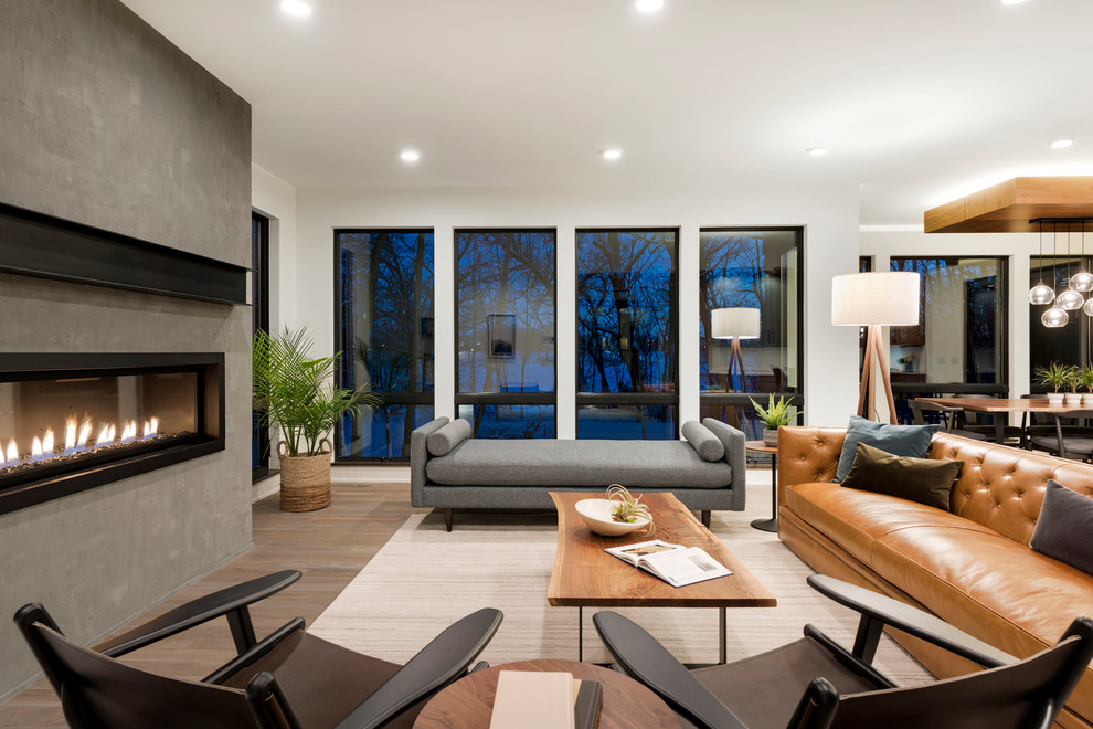 This is an example of a large modern open plan living room in Minneapolis with white walls, light hardwood flooring, a ribbon fireplace and a concrete fireplace surround.