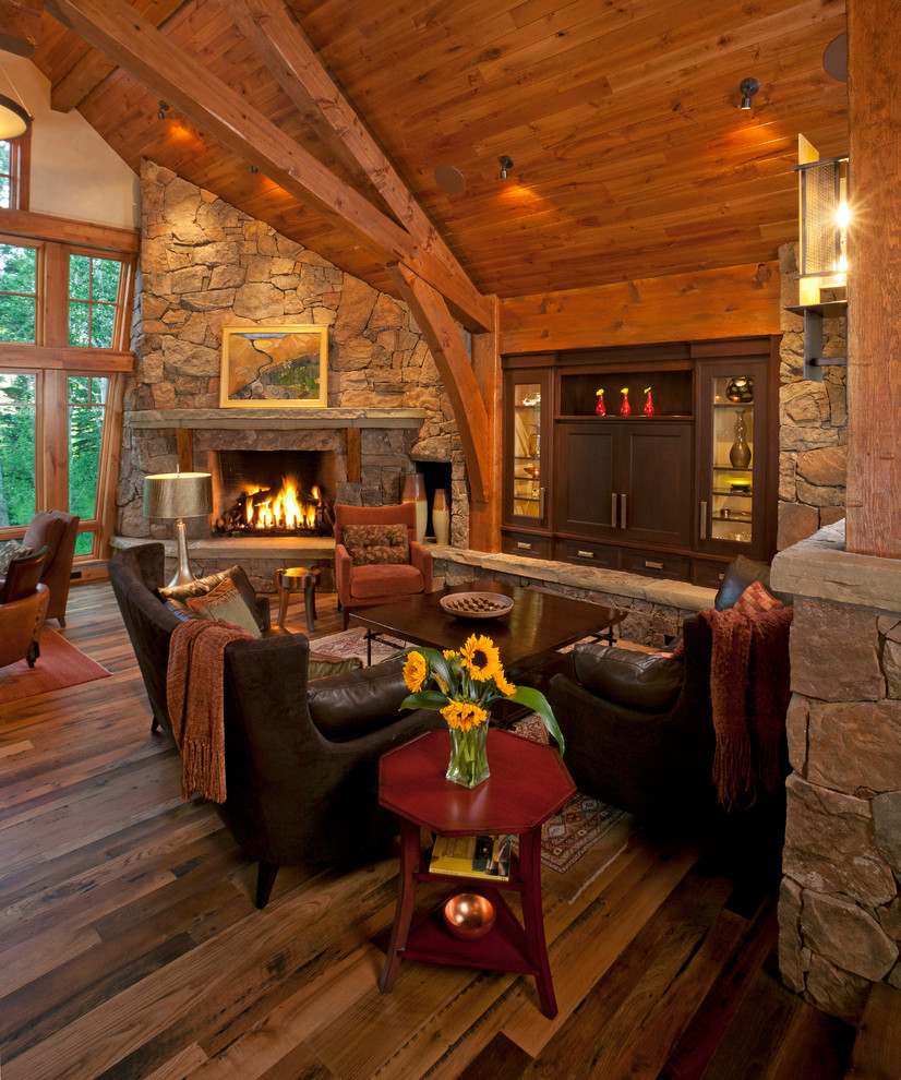This is an example of a rustic open plan living room in Denver with medium hardwood flooring, a corner fireplace, a stone fireplace surround, a built-in media unit and brown floors.