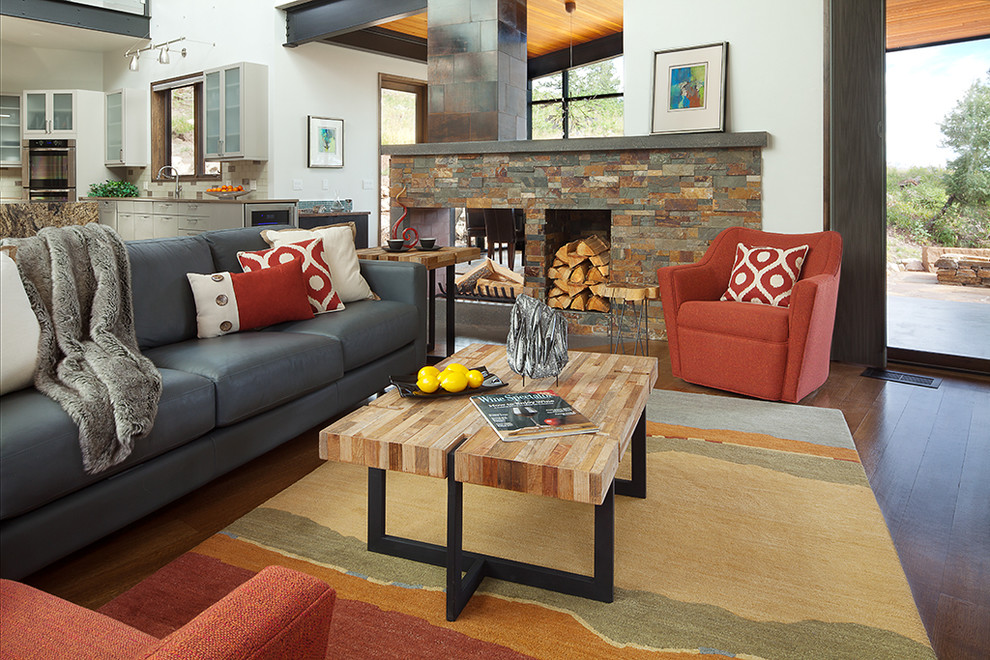 Großes, Offenes Modernes Wohnzimmer mit grauer Wandfarbe, braunem Holzboden, Tunnelkamin, Kaminumrandung aus Stein und TV-Wand in Albuquerque